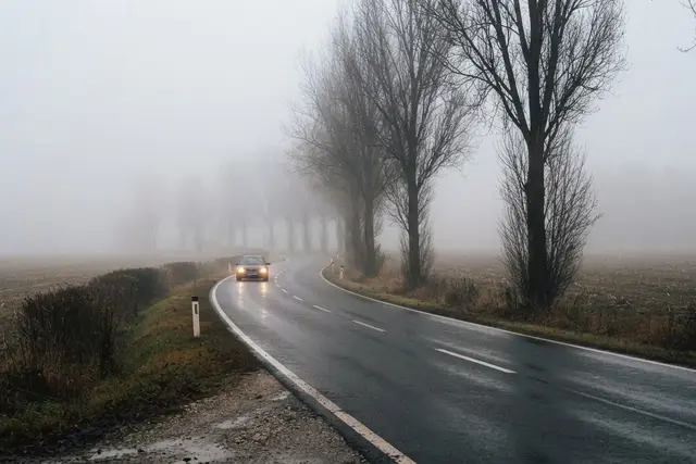 Nebel Autofahren: Landstraße in Oberösterreich bei dichtem Morgennebel mit Scheinwerfern