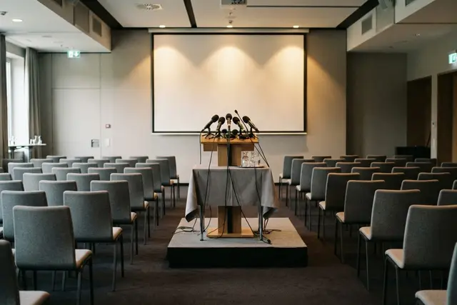 Pressekonferenz organisieren: vorbereiteter Raum mit Podium und Mikrofonen in Klagenfurt