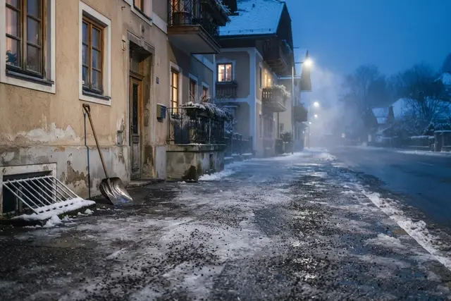 Räumpflicht: gestreuter Gehsteig vor einem Wohnhaus an einem frostigen Wintermorgen