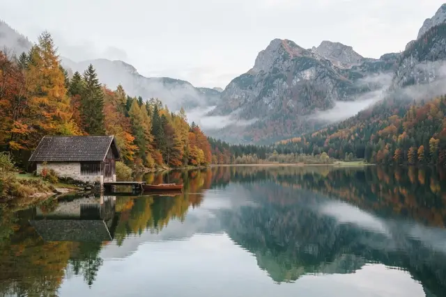 Salzkammergut Ausflug: herbstlicher Bergsee mit Bootshaus und verfärbten Wäldern