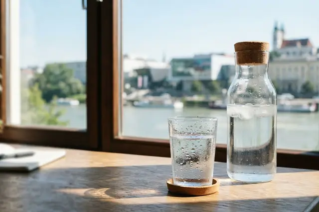 Wasser trinken: Karaffe mit Leitungswasser und Glas auf einem Schreibtisch in Linz